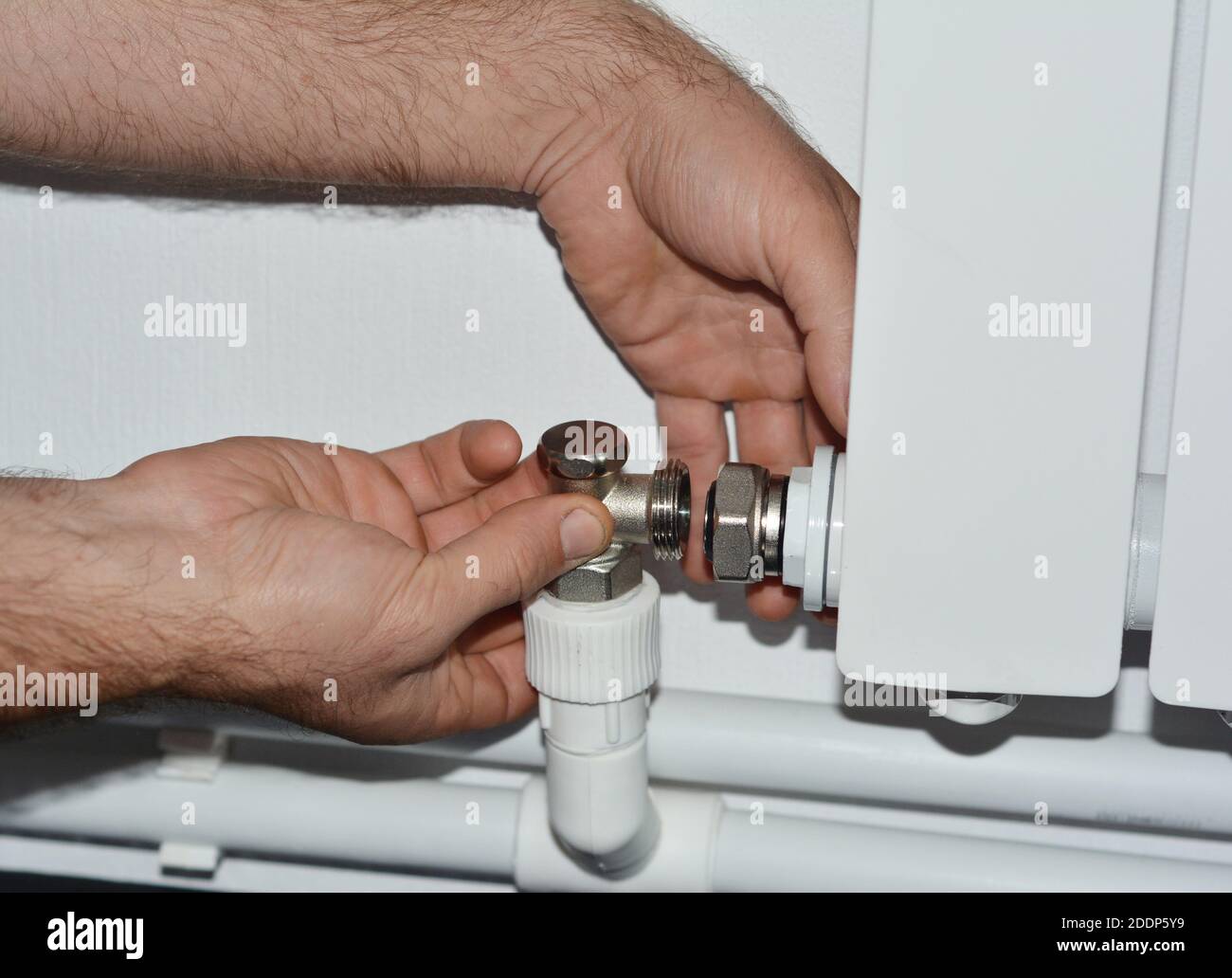Two-pipe water central heating system installation: a plumber is connecting  a plastic pipe line, faucet and a radiator valve Stock Photo - Alamy