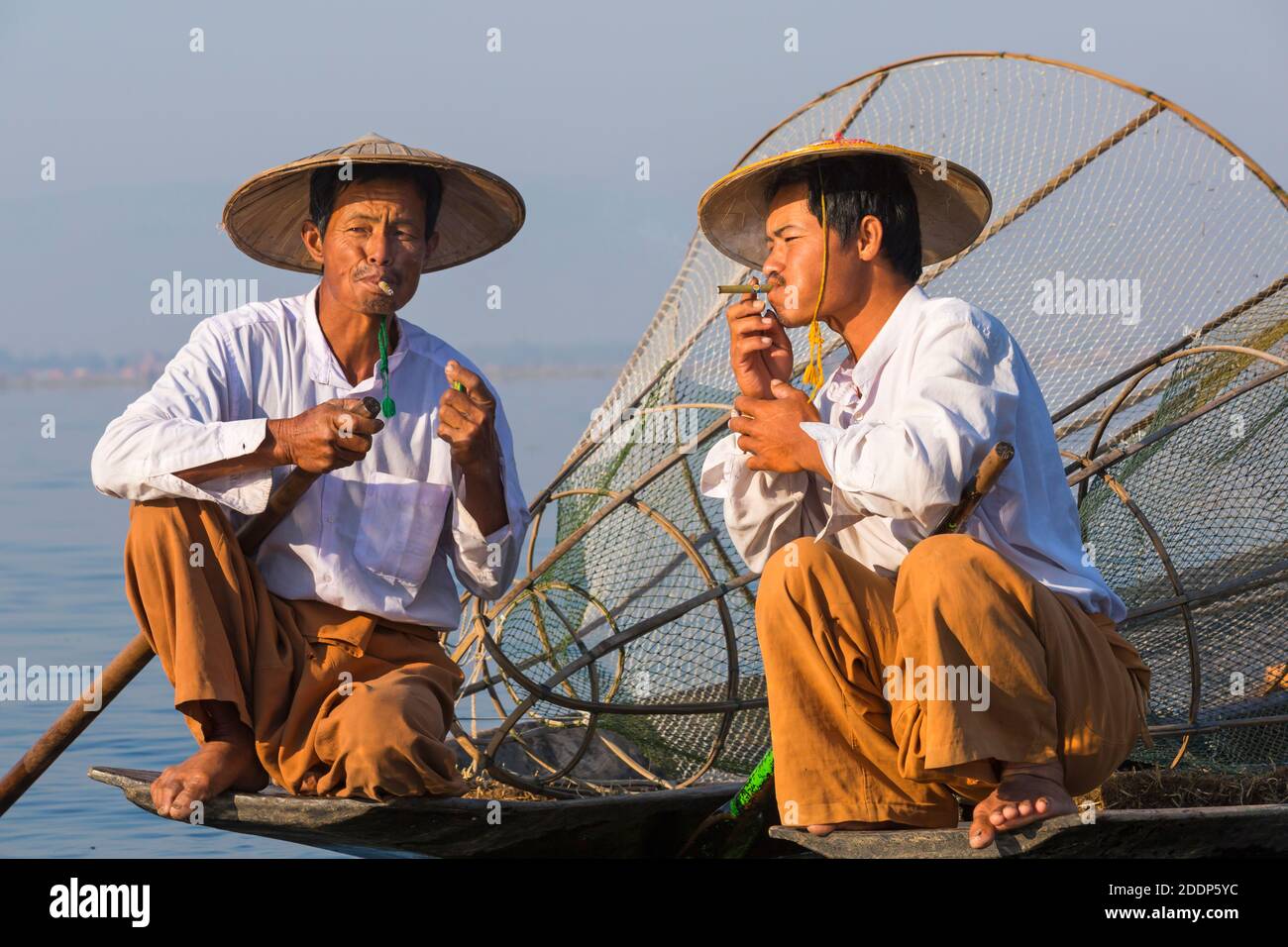 Intha leg rowing fishermen at Inle Lake, Myanmar (Burma), Asia in February - wearing conical hats hat, having a rest and smoke, smoking cigar cigars Stock Photo