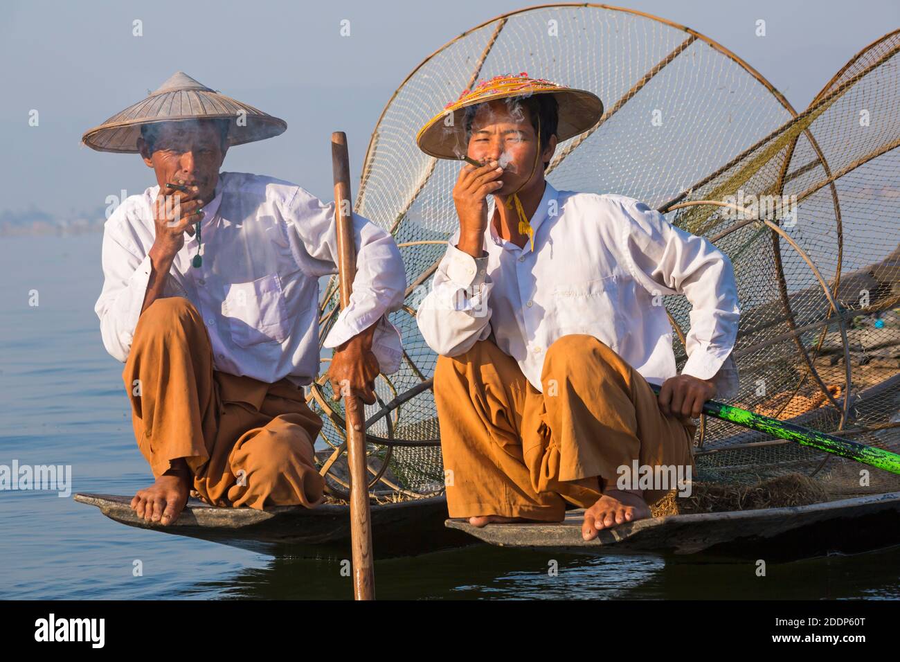 Intha leg rowing fishermen at Inle Lake, Myanmar (Burma), Asia in February - wearing conical hats hat, having a rest and smoke, smoking cigar cigars Stock Photo