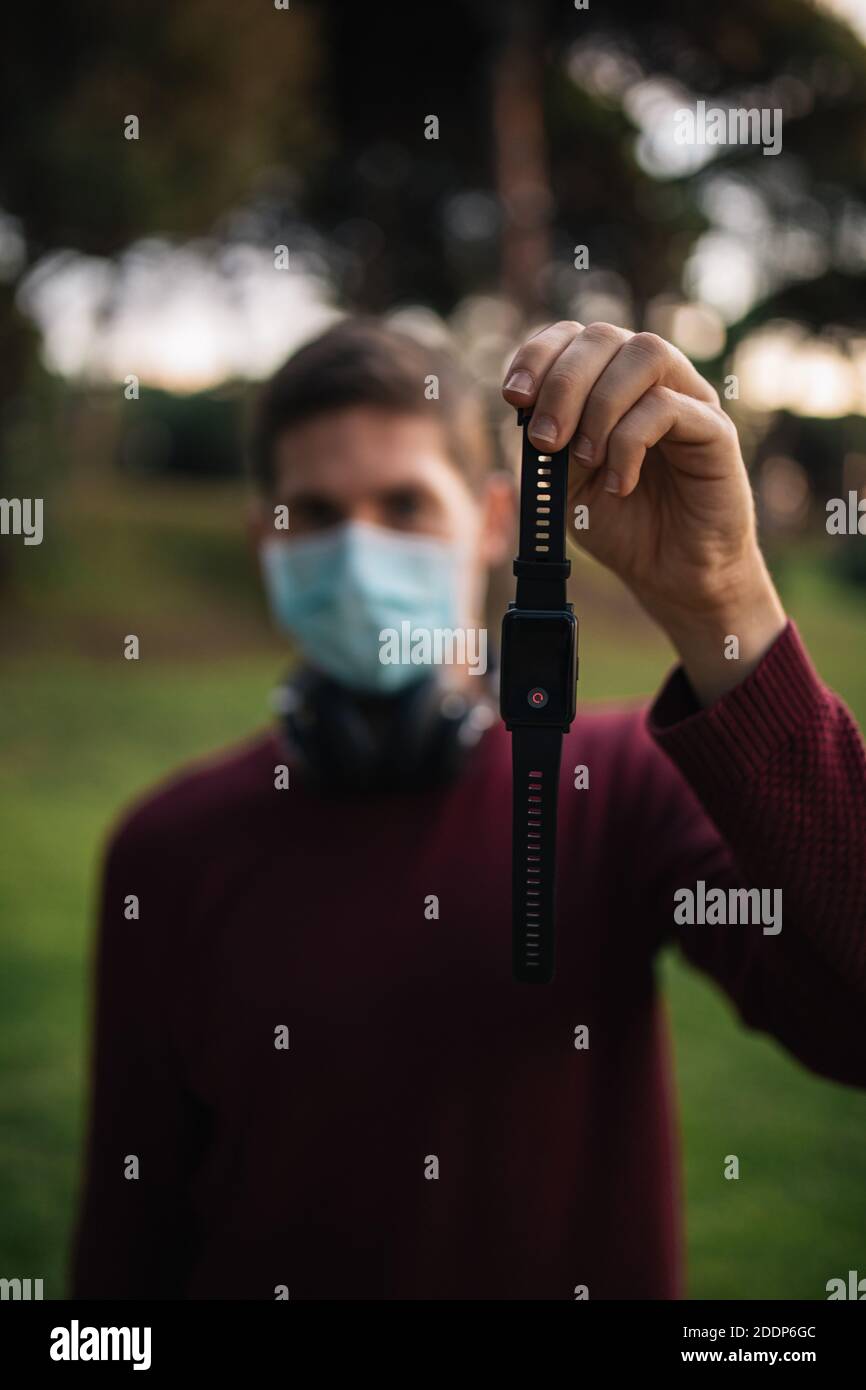Man with mask holding a smart watch showing the pulses. Concept of ...