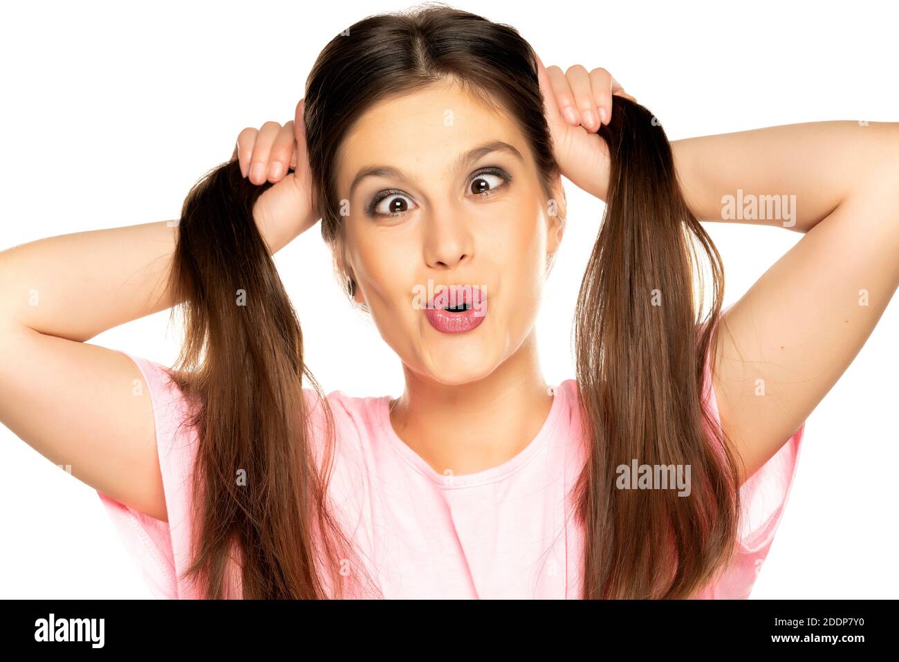 Young funny woman with pony tails make a faces on white background Stock Photo