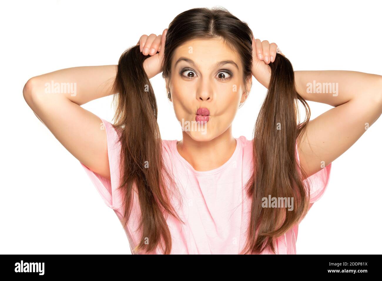 Young funny woman with pony tails make a faces on white background Stock Photo