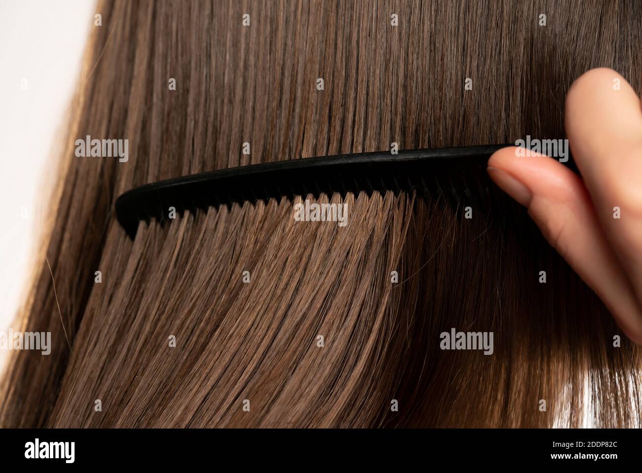 Closeup of young woman combing her hair Stock Photo