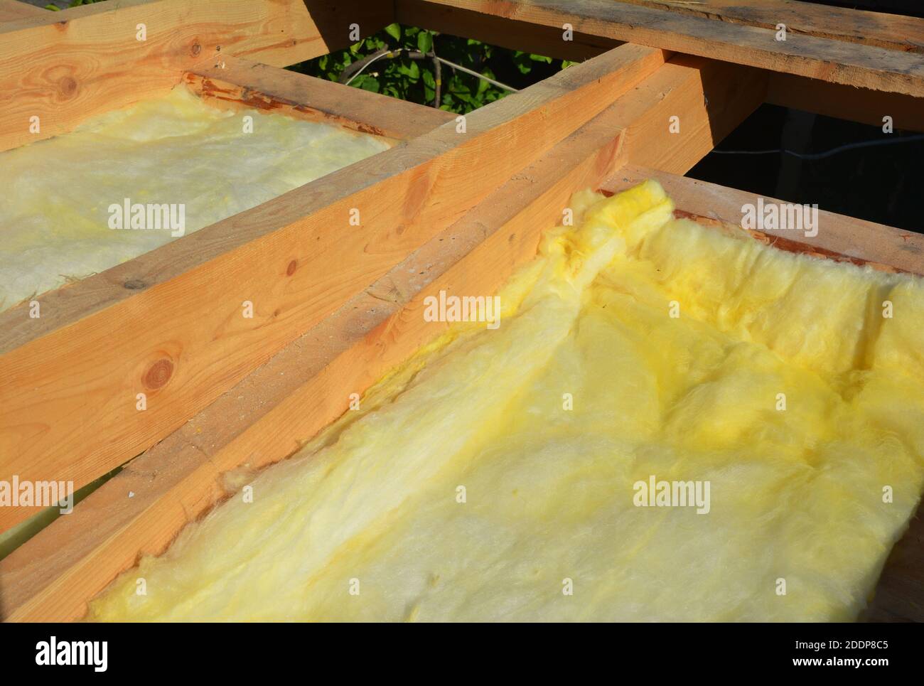 A closeup on mineral wool blanket installation between wooden ceiling