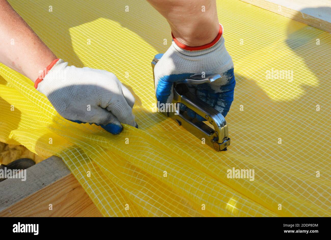 A building contractor is installing vapor barrier, plastic sheeting