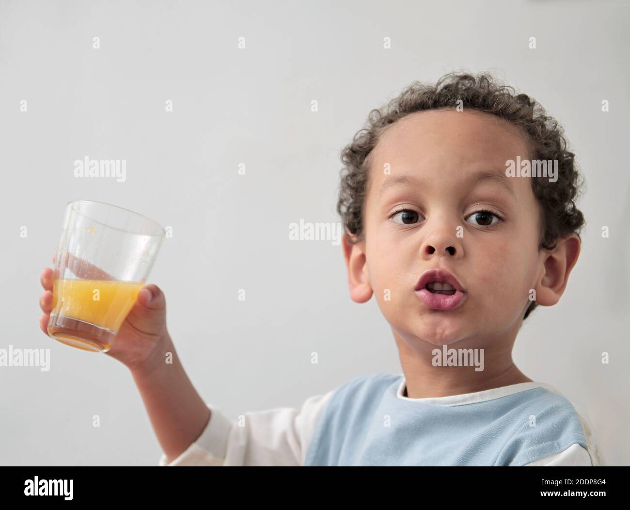 child drinking a glass of orange fruit juice promoting healthy eating