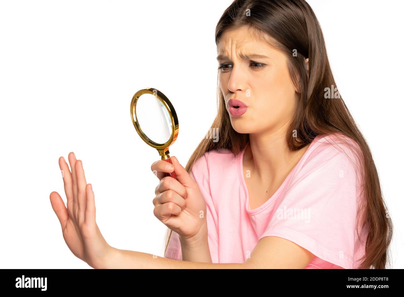 Young worried woman looking her nails with magnifying glass on white background Stock Photo