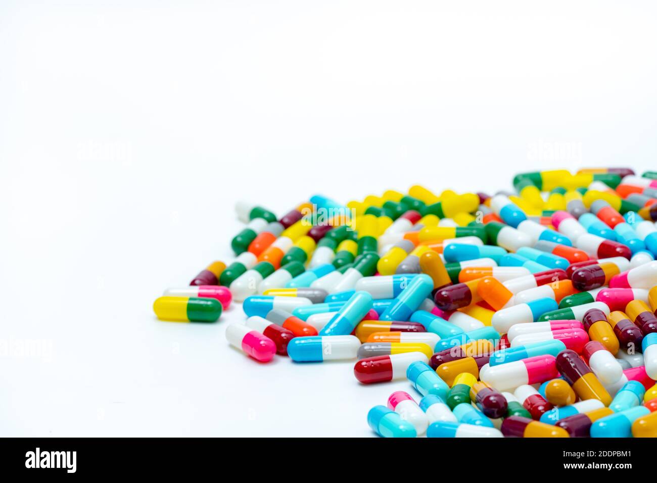 Heap of multi-colored antibiotic capsule pills on white background. Antibiotic drug resistance. Antimicrobial drugs. Pharmaceutical industry. Stock Photo