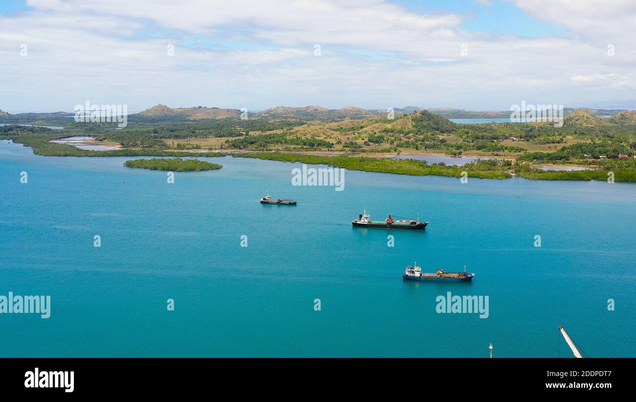 Aerial view of cargo ships leaving sea harbour at sunny day, islands on background. Tapal Wharf, Bohol, Philippines. Stock Photo