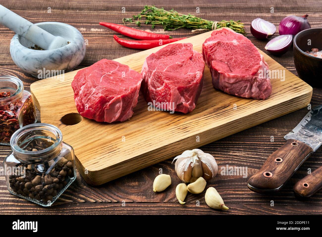 Marinated raw beef steak with spice on wooden table Stock Photo