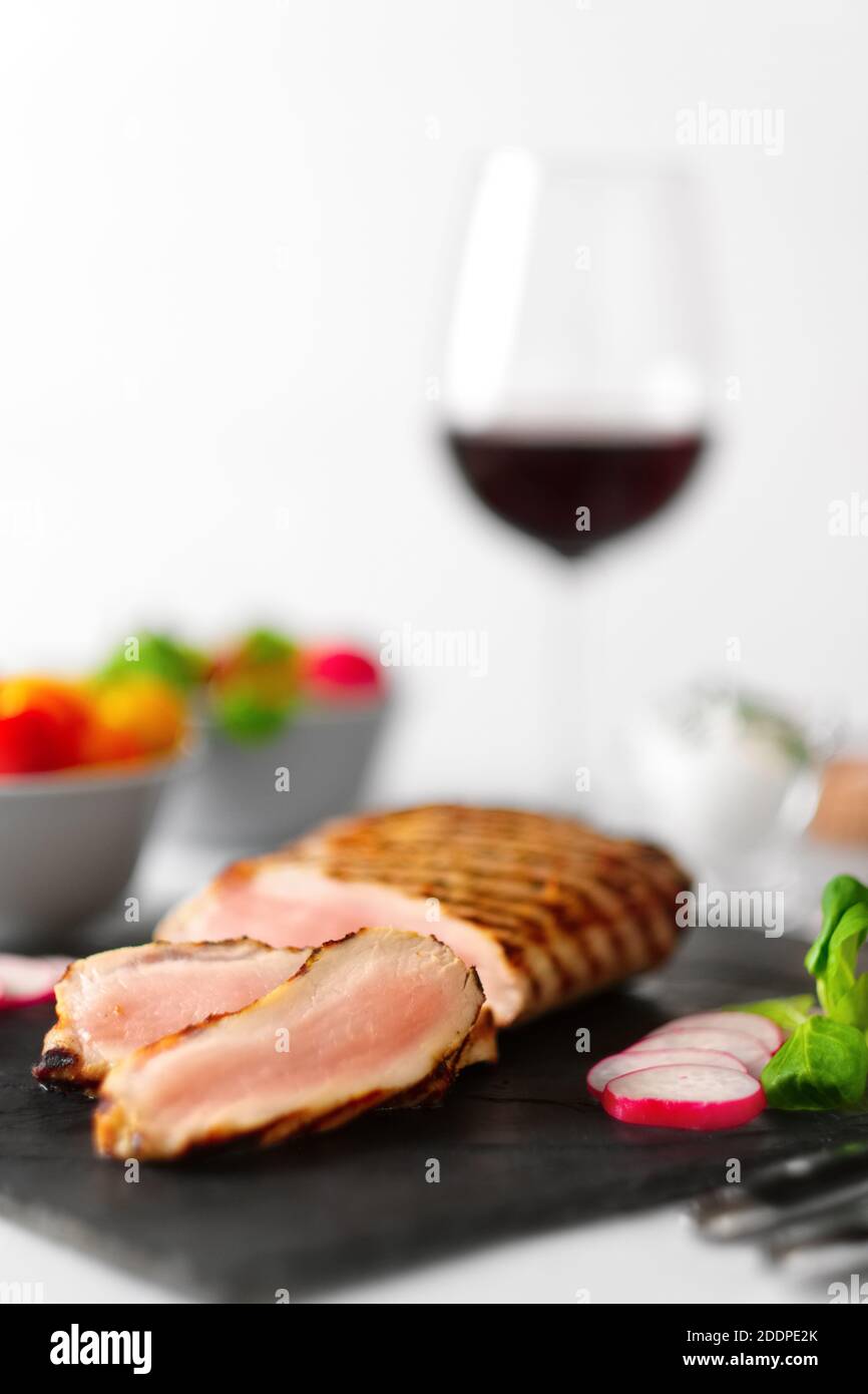 Grilled beef steak medium rare on stone board with fresh vegetables and glass of red wine. Photo with shallow depth of field. Stock Photo