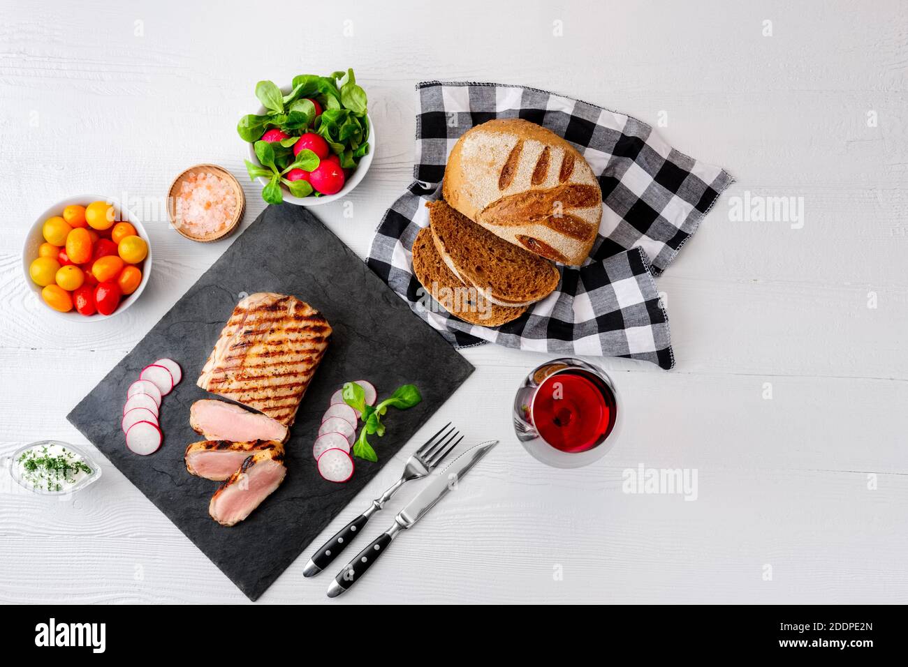 Sliced grilled roast beef with fork and knife on stone serving board. Top view with copy space for your text. Stock Photo