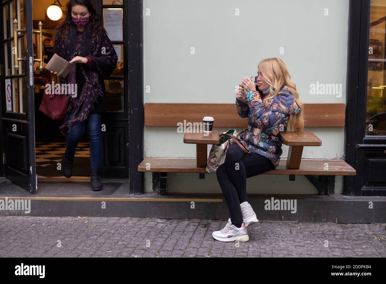 Belgrade, Serbia, Nov 24, 2020: Blond woman sitting with a cup of coffee and lighting a cigarette Stock Photo