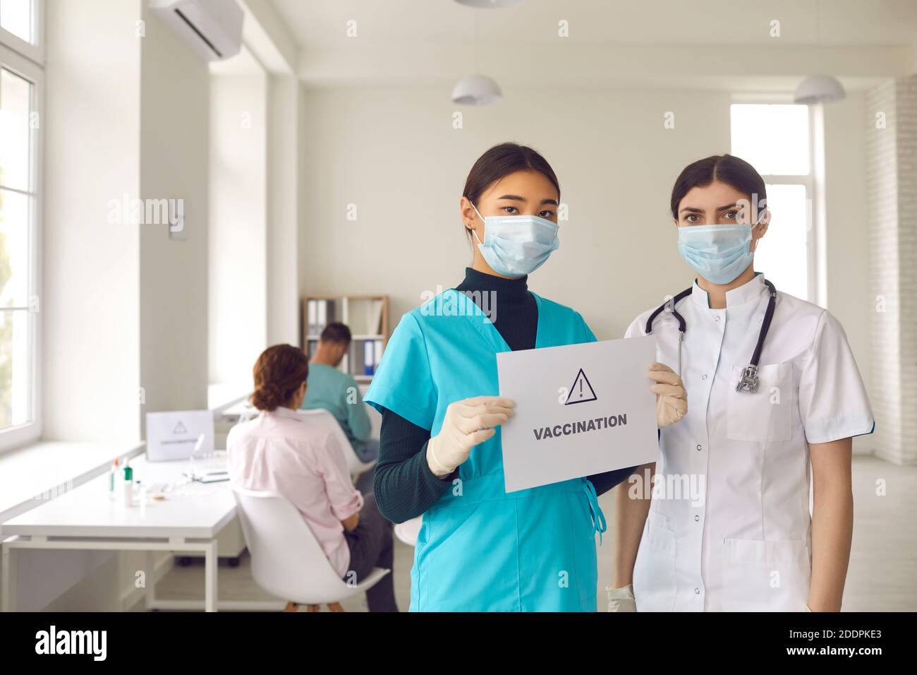 Nurses in protective mask stand with a sign in their hands with the inscription vaccination Stock Photo