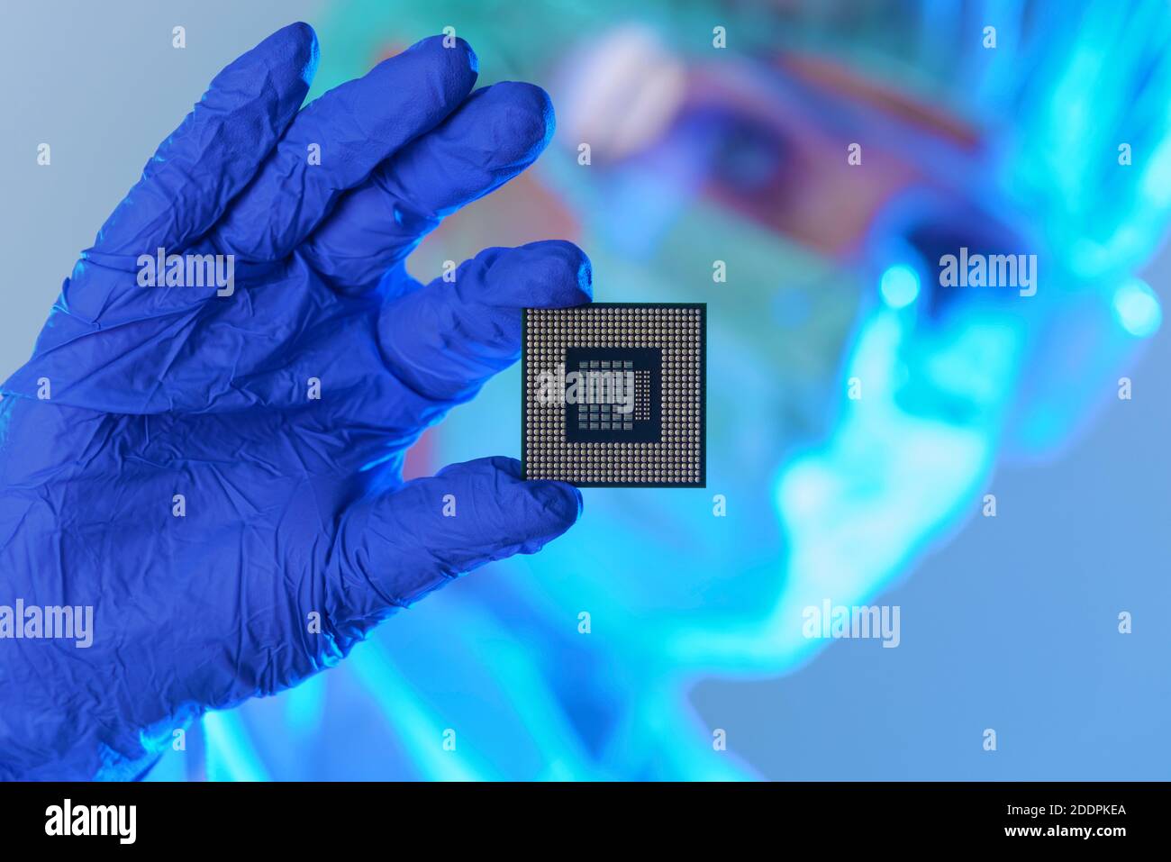 An engineer working in a laboratory wearing a special uniform and protective gloves holds new processor in hands and examines it Stock Photo