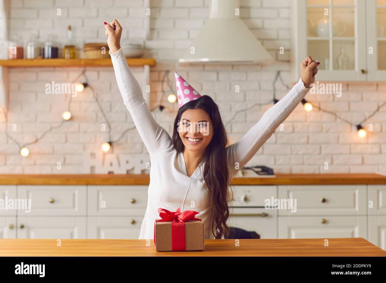 Cheerful woman celebrating her birthday at a virtual party with friends through a video call. Stock Photo
