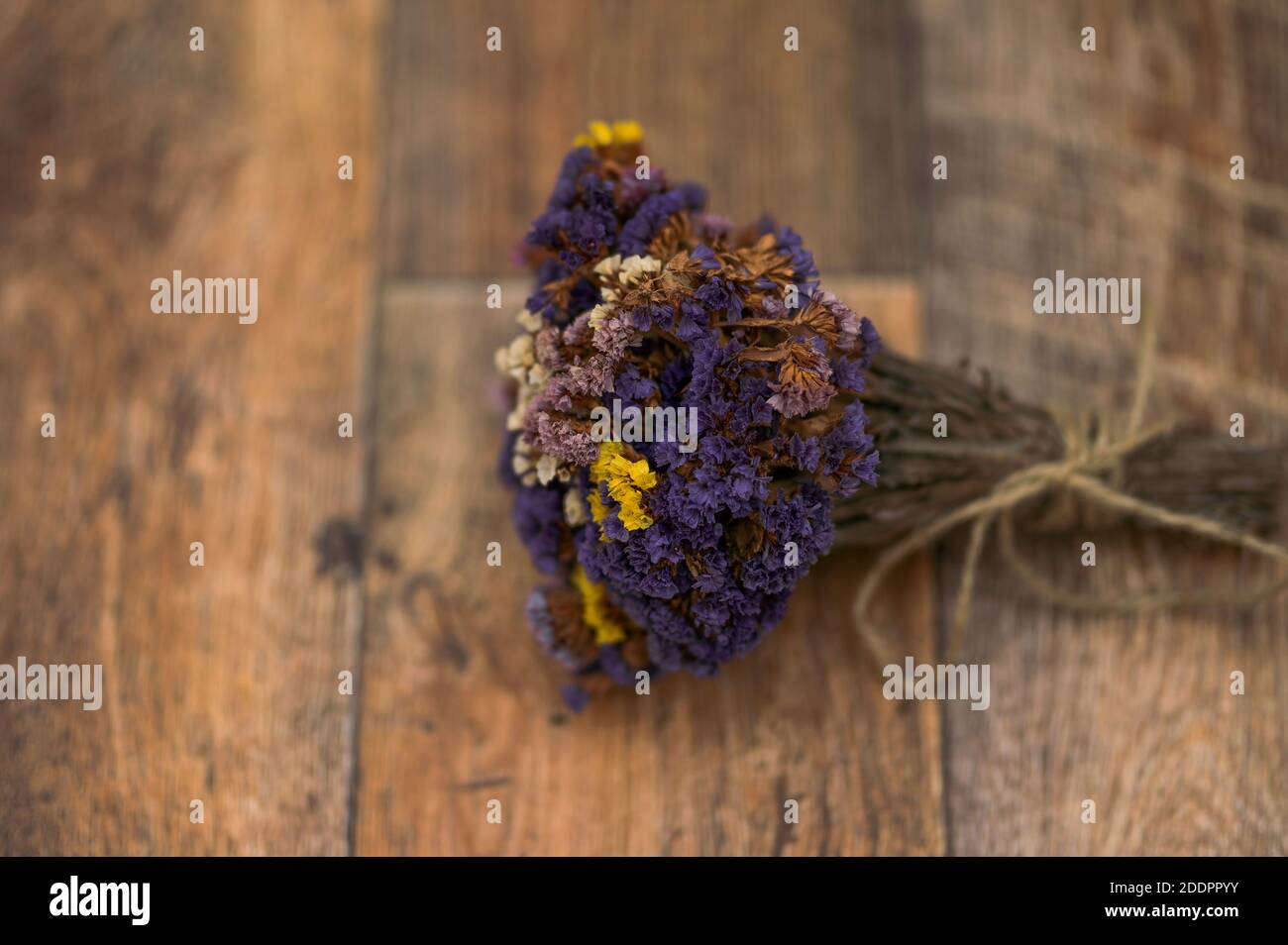 a bouquet of dried flowers, Limonium sinuatum, wavyleaf sea lavender, statice, notch leaf marsh rosemary, sea pink with a jute twine on a wooden floor Stock Photo
