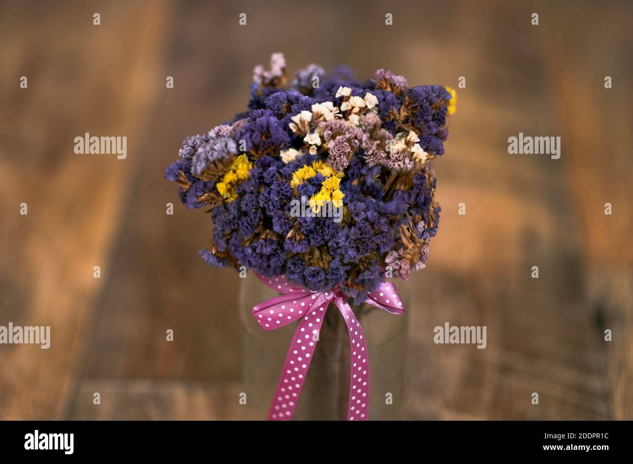 a bouquet of dried flowers, Limonium sinuatum, wavyleaf sea lavender, statice, notch leaf marsh rosemary, sea pink in a jar, pink ribbon, wooden floor Stock Photo