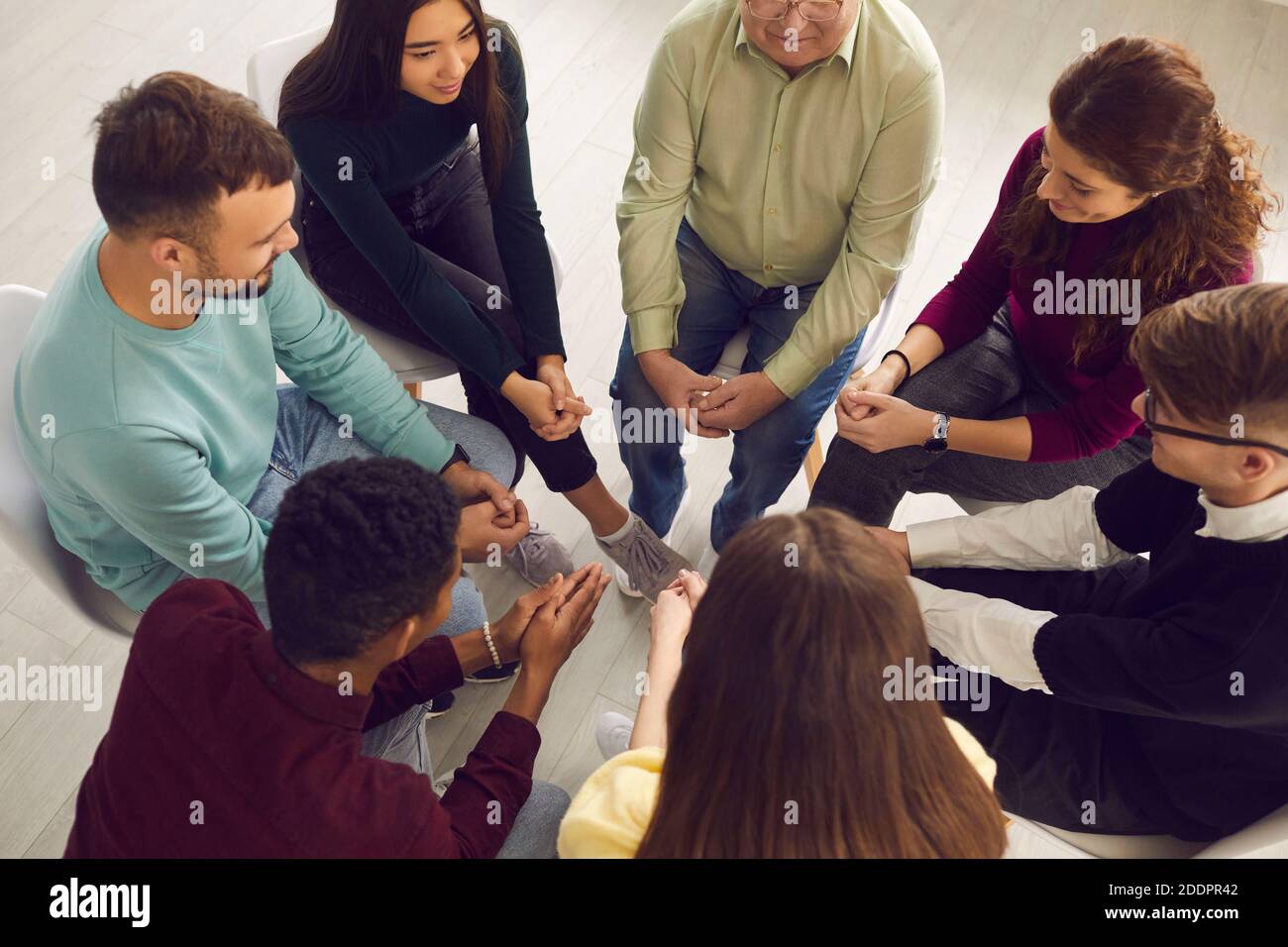 Diverse people sitting in circle and sharing their stories in group therapy session Stock Photo