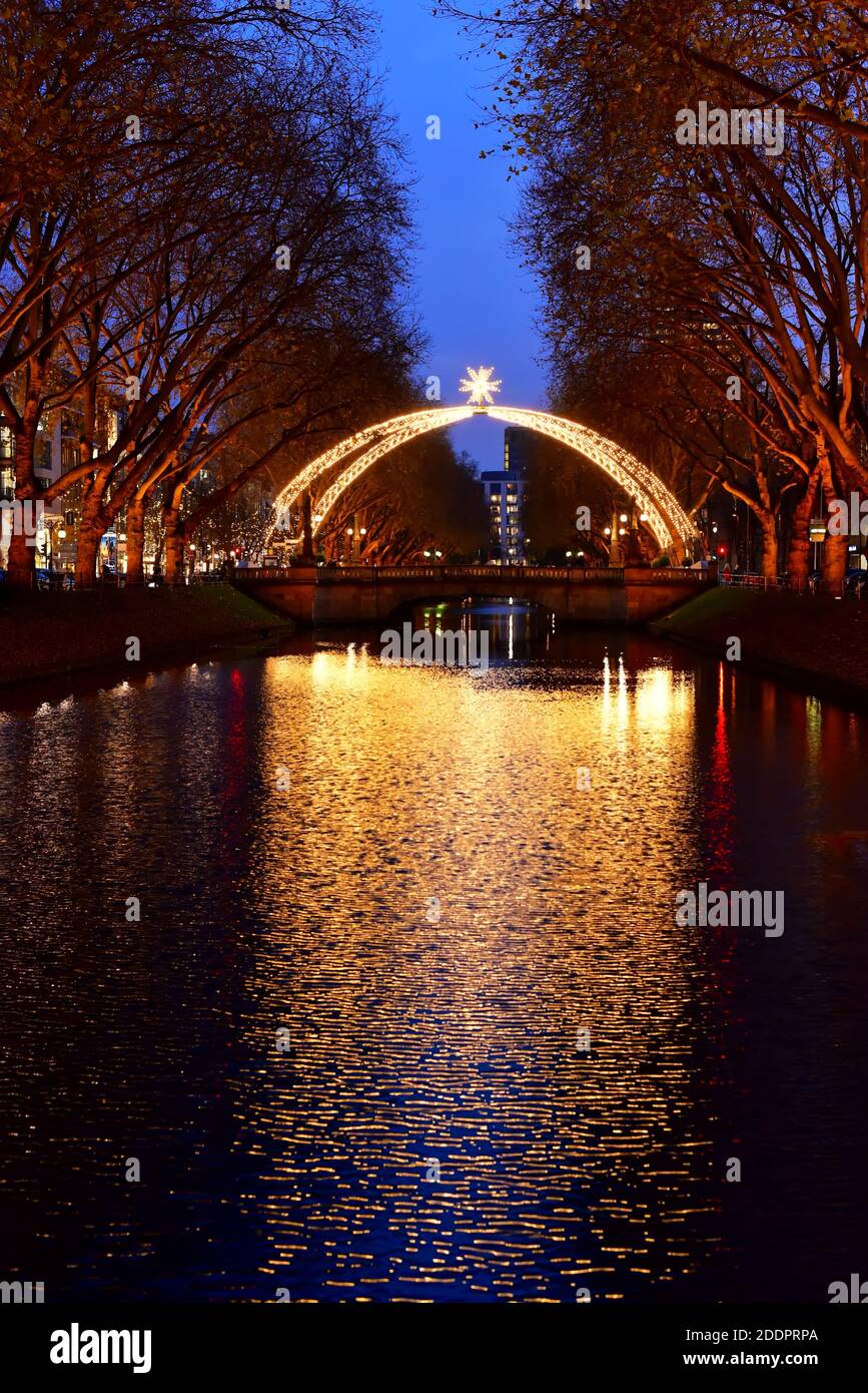 Traditional Christmas arc at Königsallee with reflection of the light in the city canal. Stock Photo