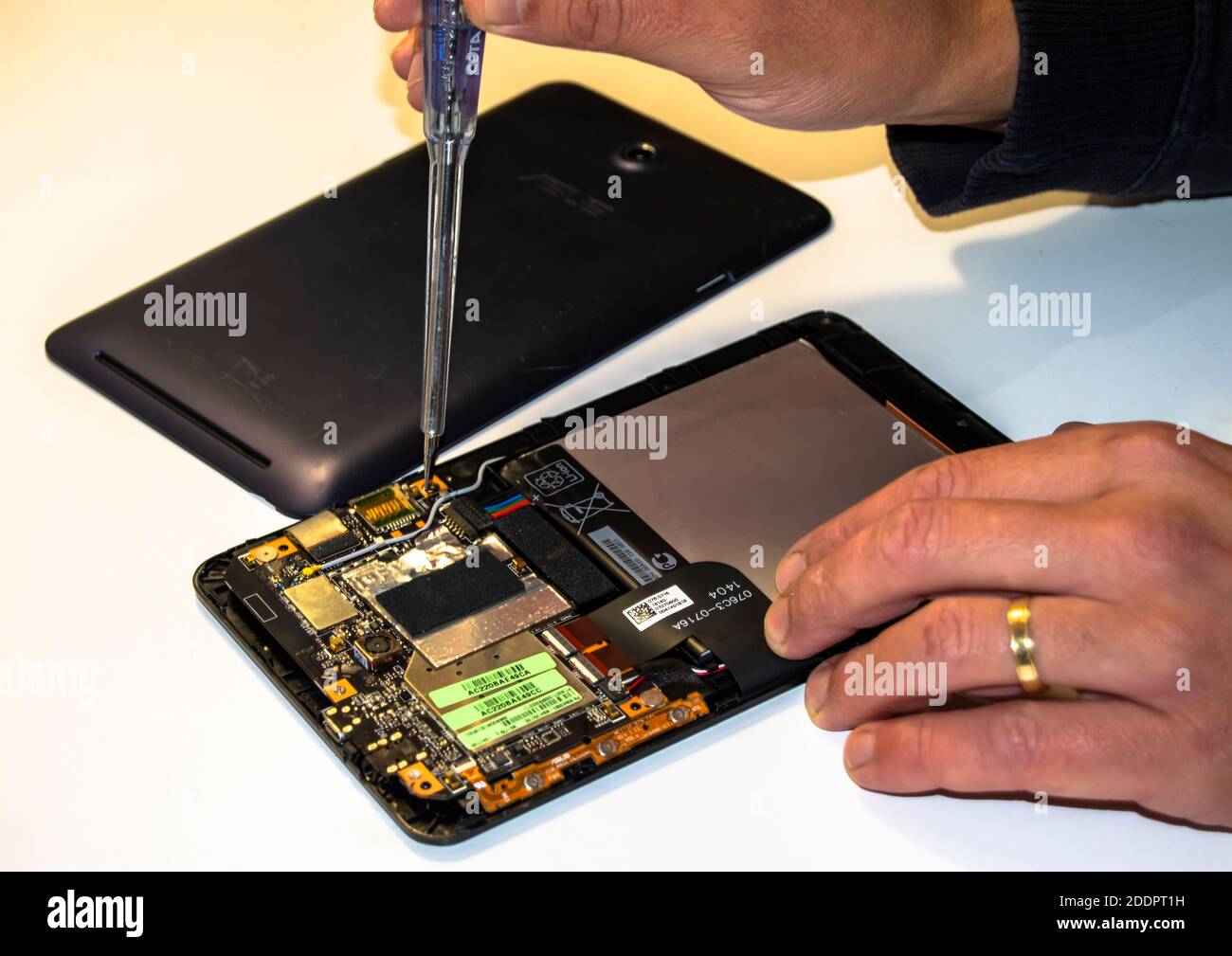 married man fixing electronics or fixing tablet issues with screwdriver Stock Photo