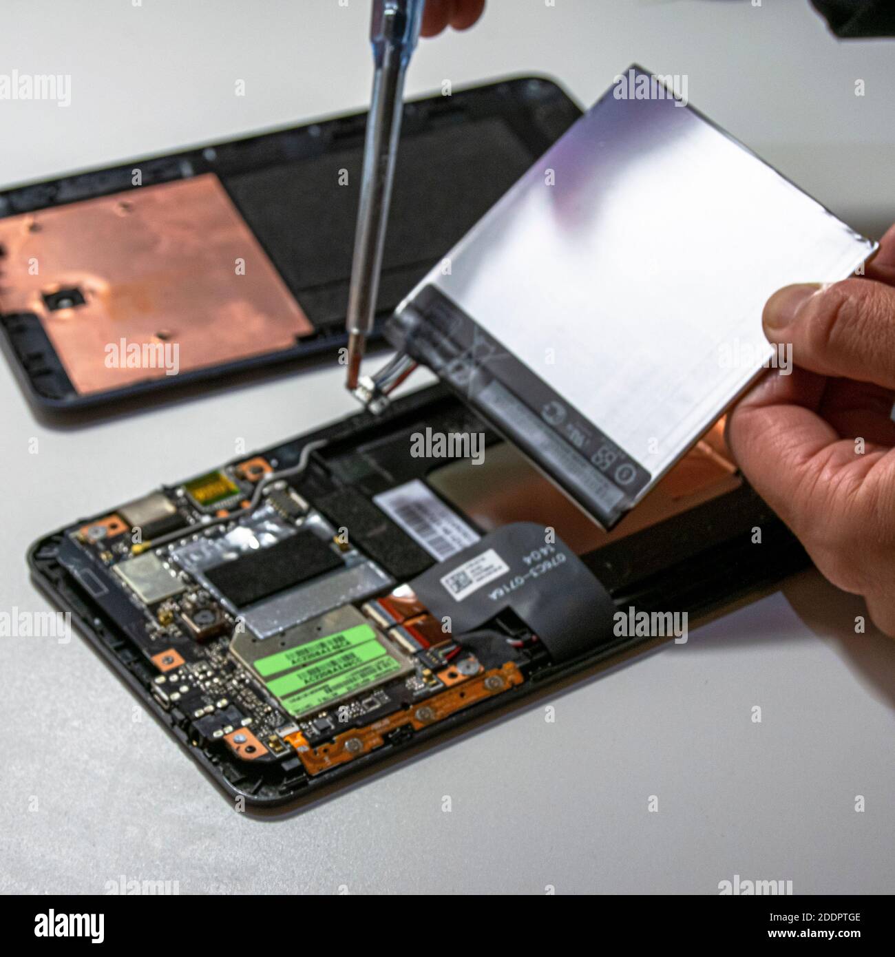 Man fixing an electronic device or fixing tablet issues by removing battery. Reparations jobs on electronics like tablets. Stock Photo