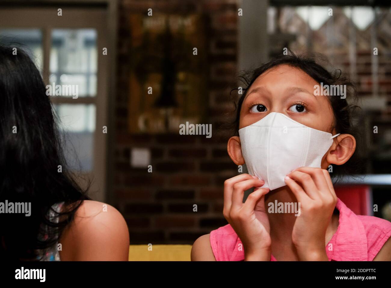 Southeast Asian Little Girl wearing White Face Mask at Home Stock Photo