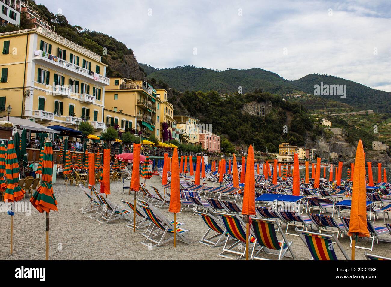 Monterosso al Mare, Italy - July 8, 2017: People Sitting in a Cafe on Fegina Beach with Traditional Colorful Houses in in the Background on a Summer D Stock Photo
