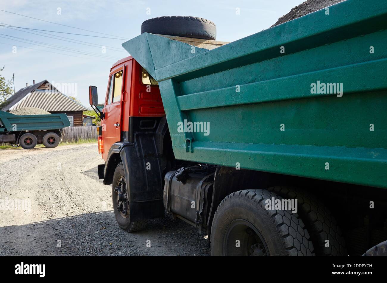 Big dump truck on suburban street. Waiting for dumping gravel for building and reconstruction roadway Stock Photo