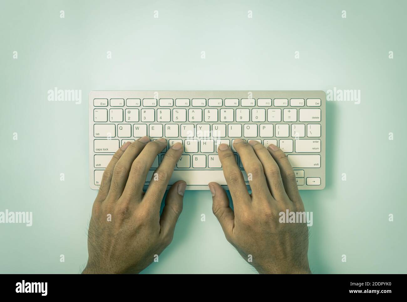 Hand of Businessman Typing Portable Computer Keyboard Keys or Keyboard Button on Top Table or Top View on Blue Pastel Minimalist Background in Vintage Stock Photo