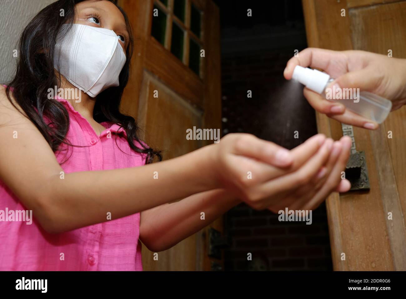 Southeast Asian teen girl hands being sprayed with hand sanitizer before entering the house. Protection against infectious virus Hygiene and healthy Stock Photo