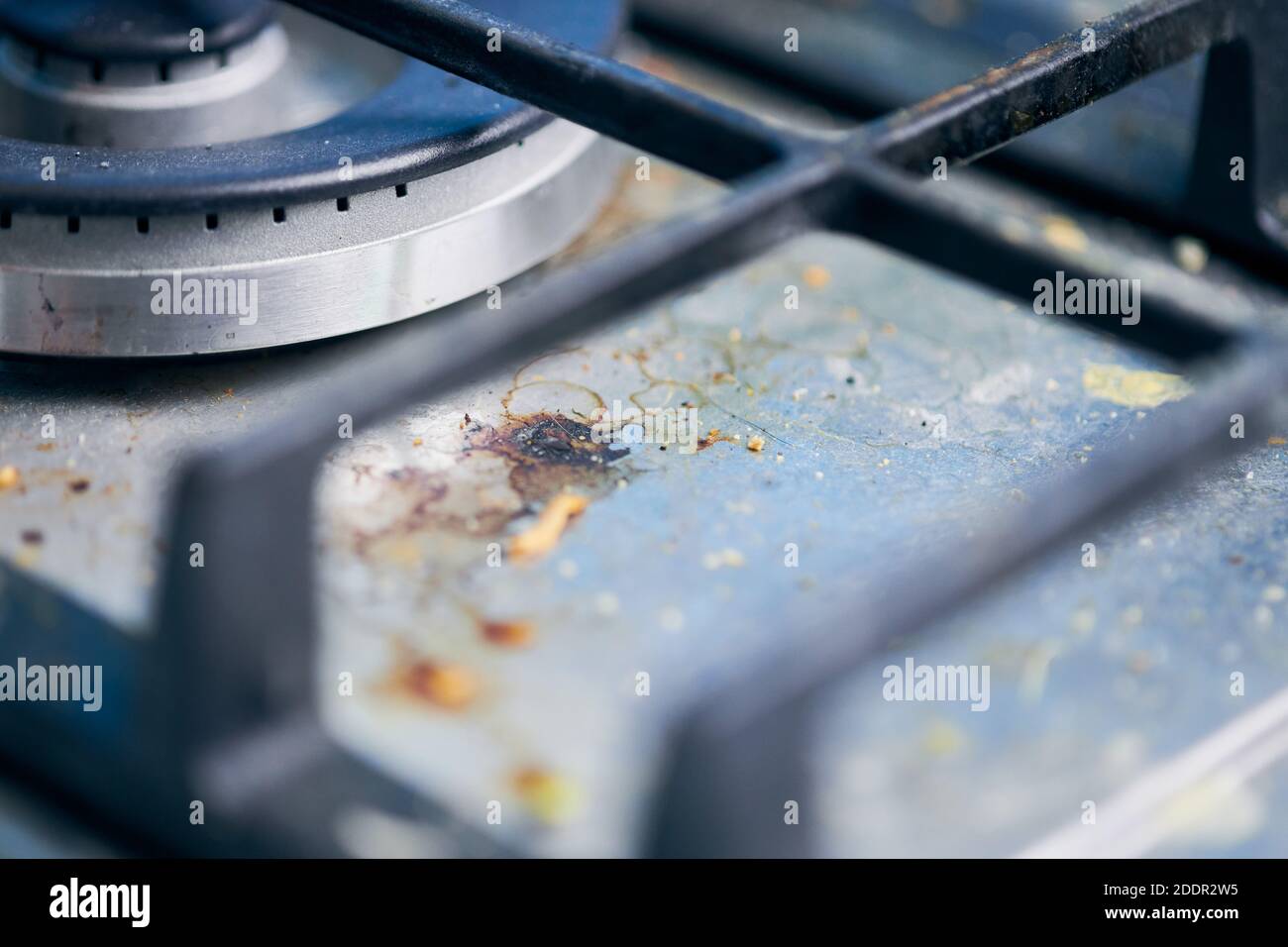 Dirty gas stove top with food leftovers. Unclean steel kitchen cooktop