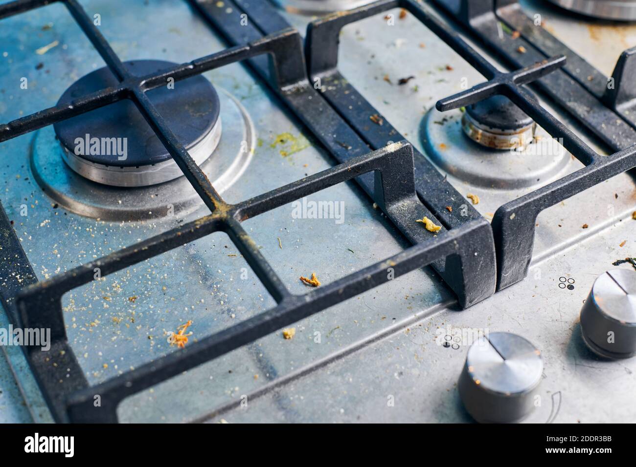 Dirty gas stove top with food leftovers. Unclean steel kitchen cooktop