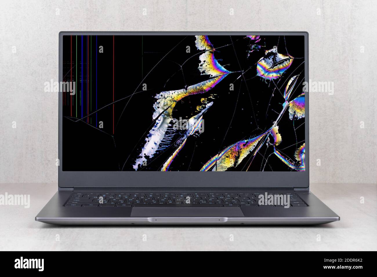 laptop with a broken screen in color spots and cracks on a gray ...
