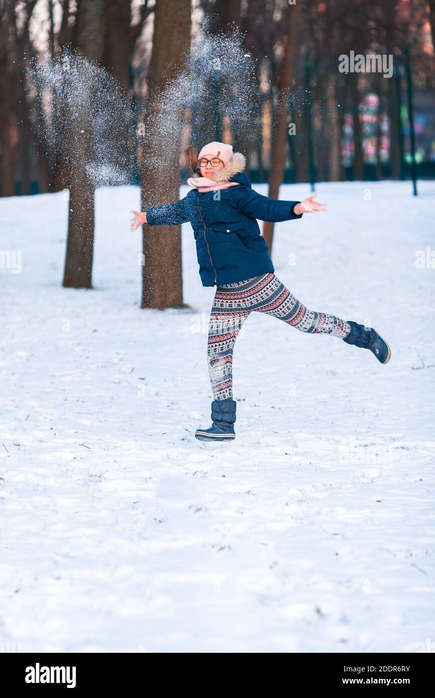 Happy teenage girl having a snowball fight, ready to throw a snowball, playing snowballs in winter park Stock Photo