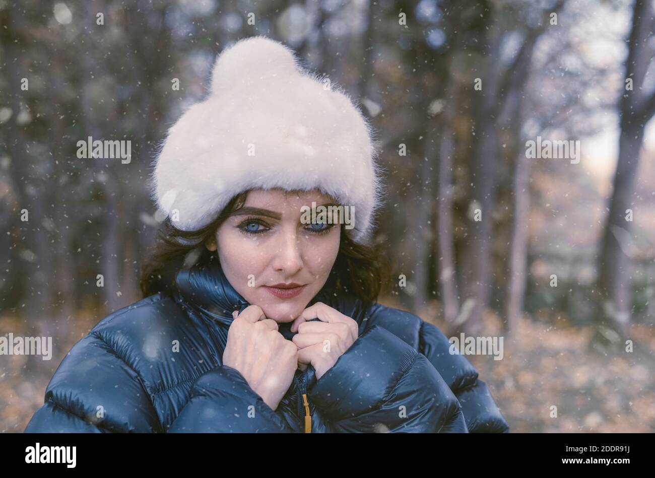 Portrait of pretty young woman wearing a padded jacket and a hat in the English countryside. Stock Photo