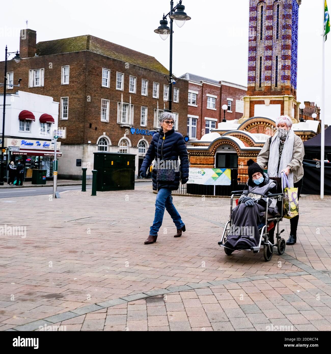 London UK, November 26 2020, Two Elderly Woman Pushing A Man In Wheelchair Down Empty High Street During COVID-19 Lockdown Stock Photo