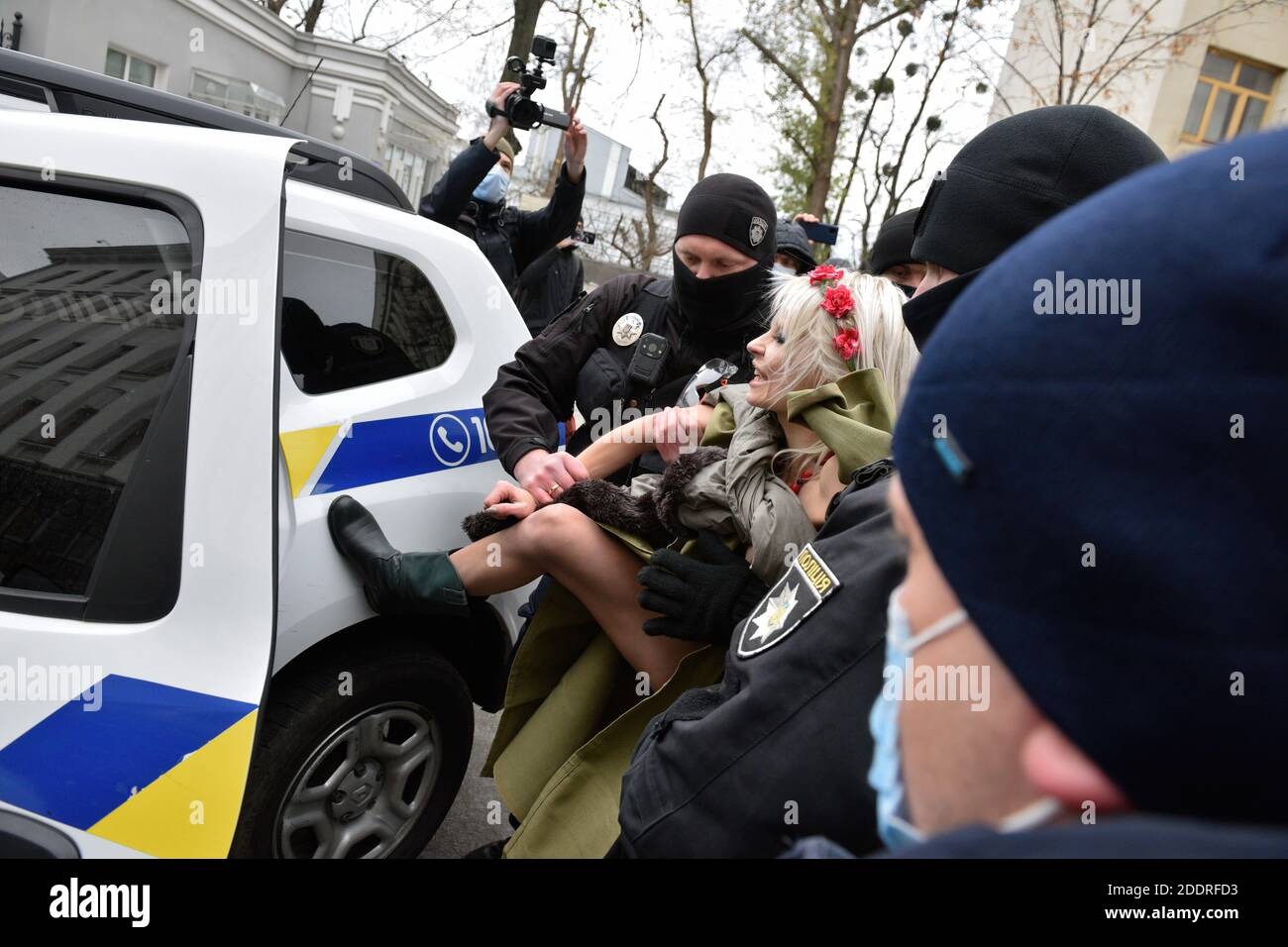 Police officers detain an activist of the women's movement FEMEN during the demonstration. An activist of the women's movement FEMEN demands the ratification of the Istanbul Convention by Ukraine during the International Day for the Elimination of Violence against Women, in front of the Presidential office building in Kiev. Stock Photo