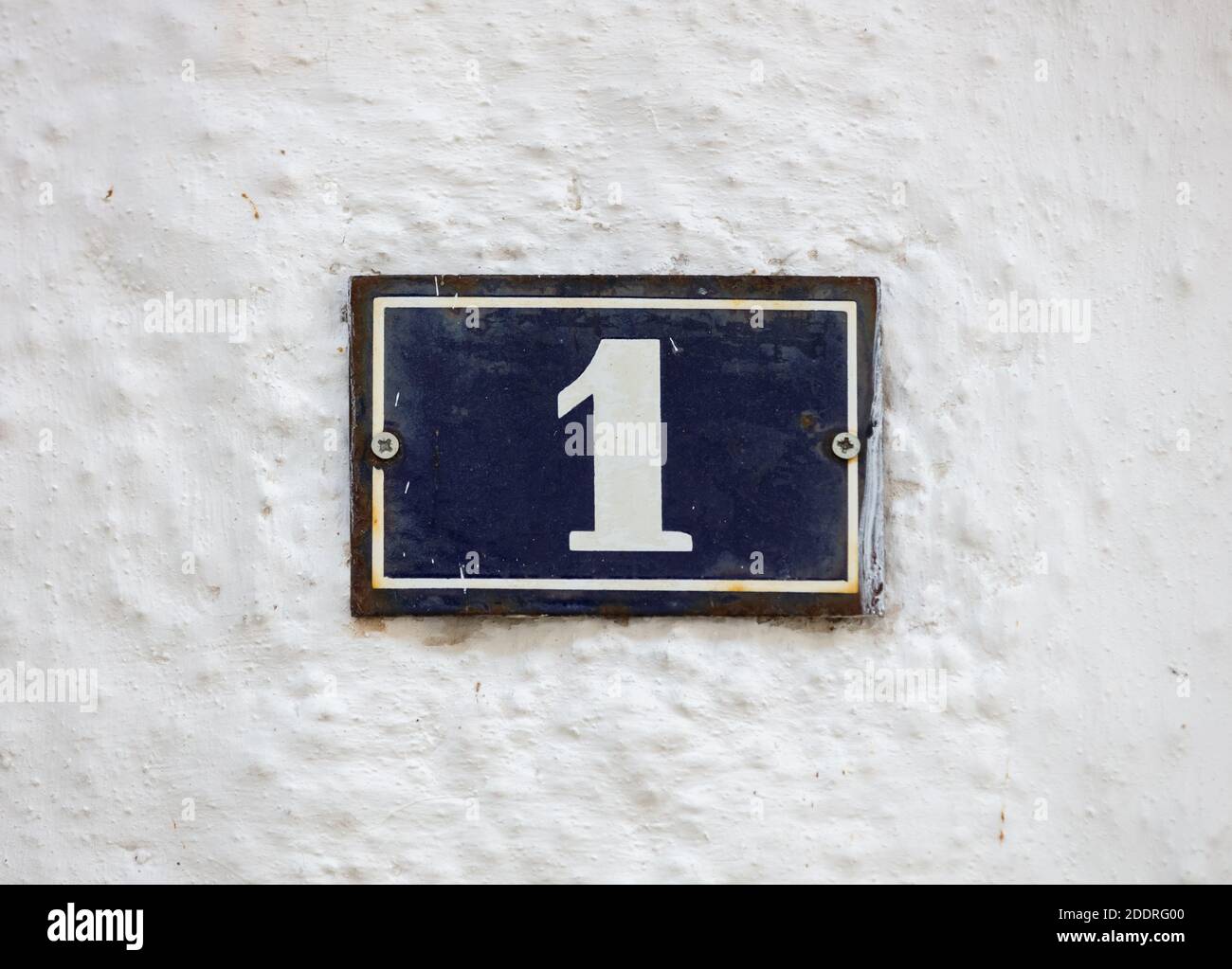 Street number one. Digit 1 on metal vintage plate mounted on whitewashed wall. Traditional house address Stock Photo