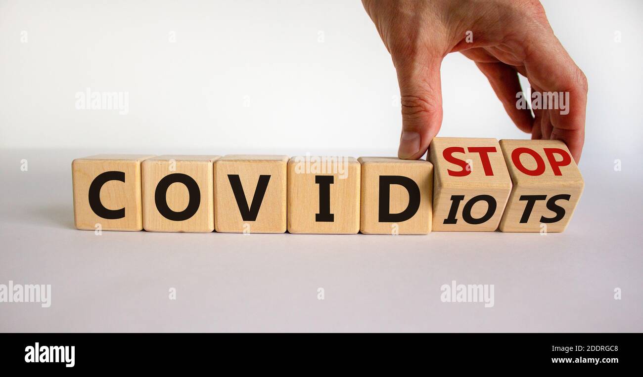 Stop covidiots. Hand turns cubes with words 'stop covidiots'. Beautiful white background. Covid-19 pandemic and stop covidiots concept. Copy space. Stock Photo