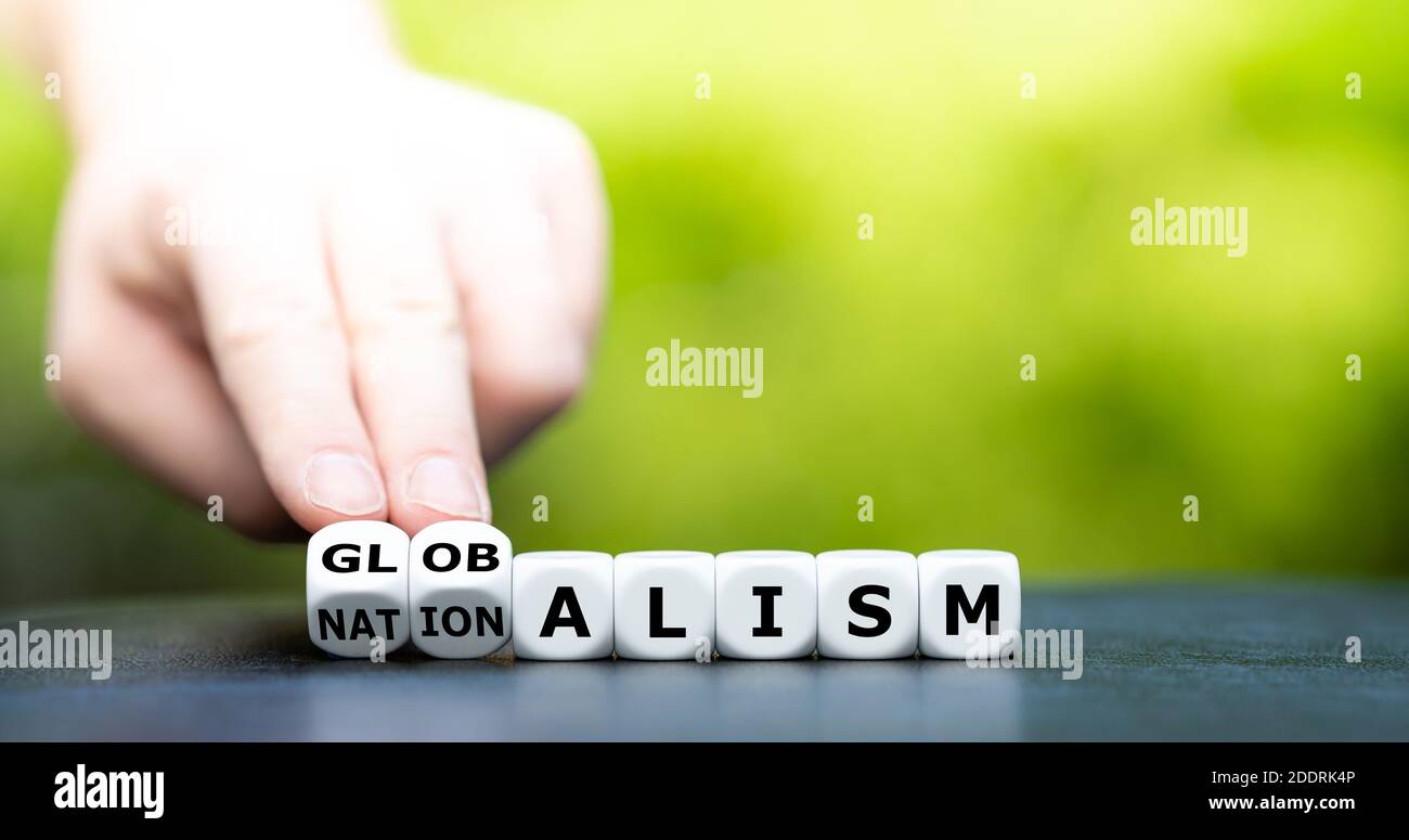 Hand turns dice and changes the word nationalism to globalism. Stock Photo