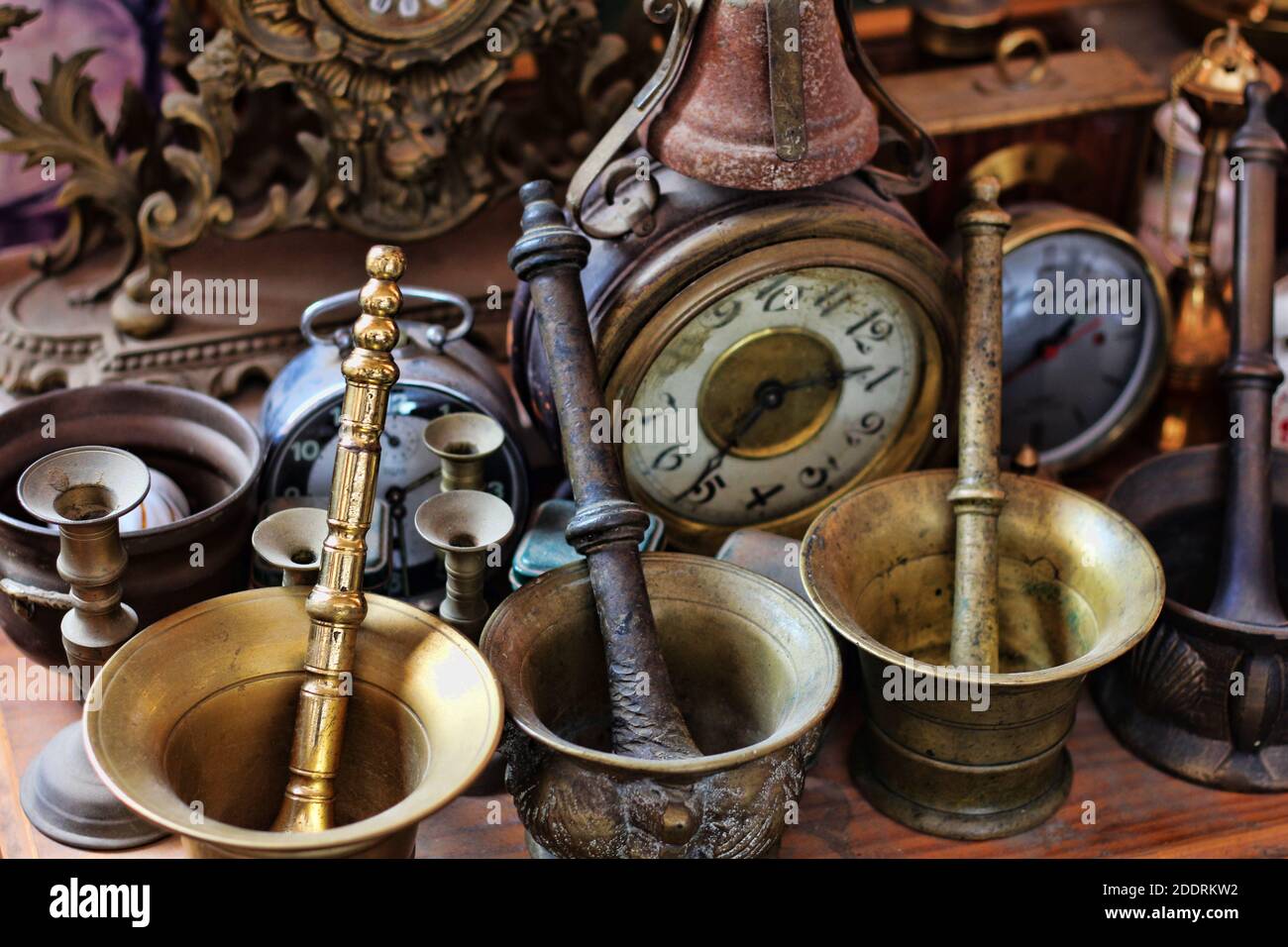 https://c8.alamy.com/comp/2DDRKW2/a-closeup-of-antique-metallic-mortars-candle-holders-alarm-clocks-and-a-table-clock-2DDRKW2.jpg