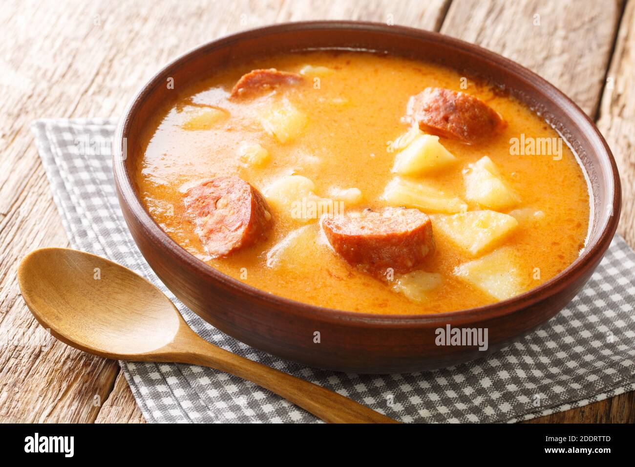 Homemade potato soup with sausages and sour cream close-up in a plate on the table. horizontal Stock Photo