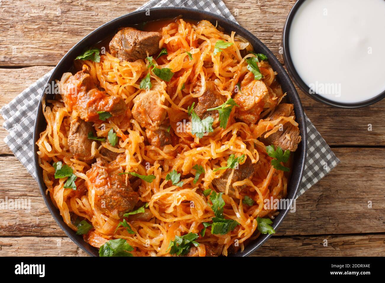 Sauerkraut stew with pork and paprika close-up in a plate on the table. horizontal top view from above Stock Photo