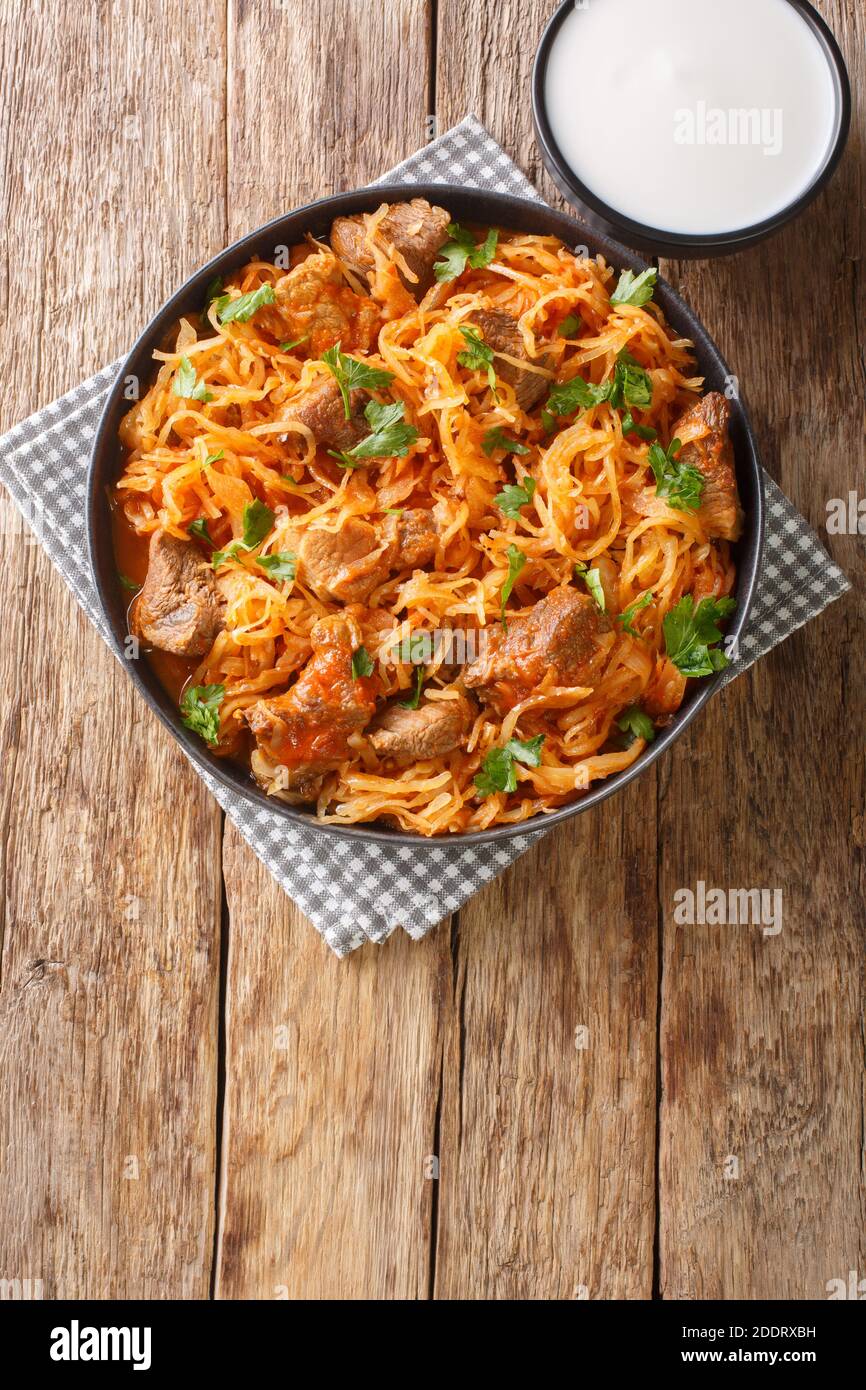Szekely Gulyas or Szegedin goulash with pork, onions and sauerkraut in a paprika broth closeup  in the plate on the table. Vertical top view from abov Stock Photo