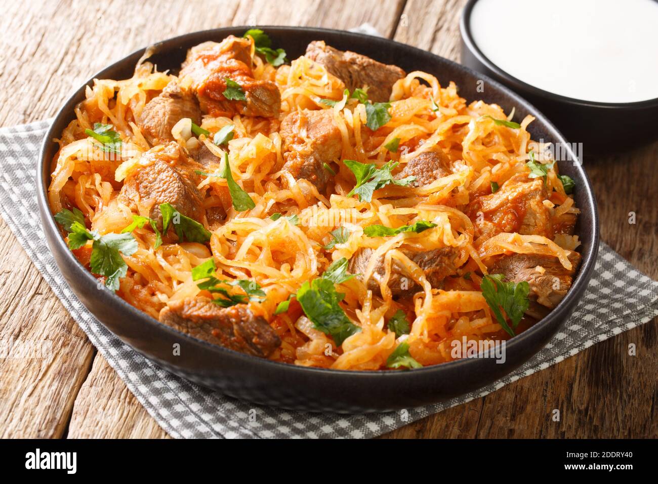 Delicious stewed sauerkraut with pork, onions and paprika close-up in a plate on the table. horizontal Stock Photo