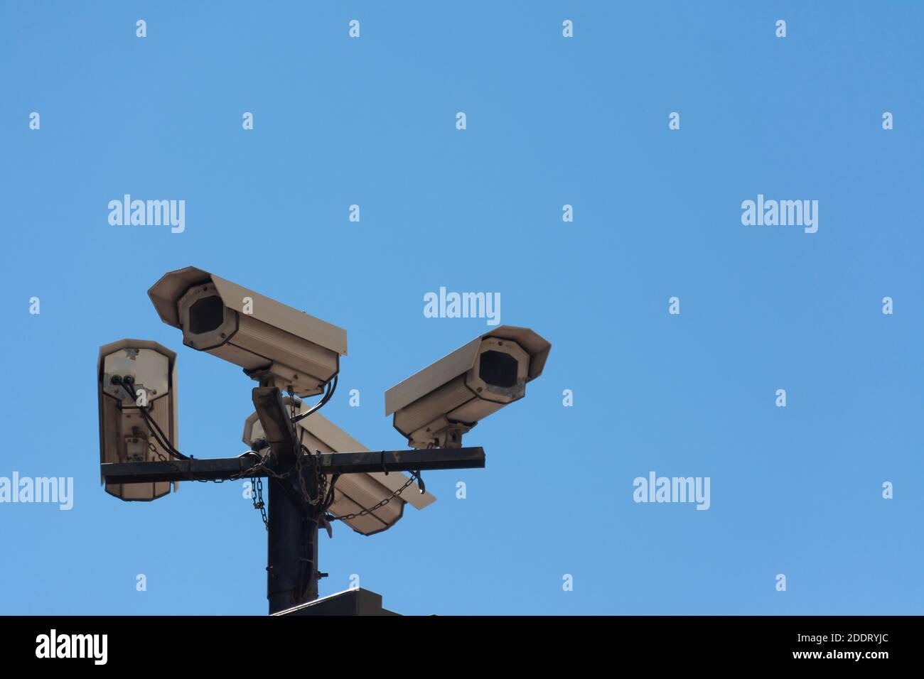 Four security cameras on a pole in the street, from below, with a blue sky. Concepts like security or privacy Stock Photo