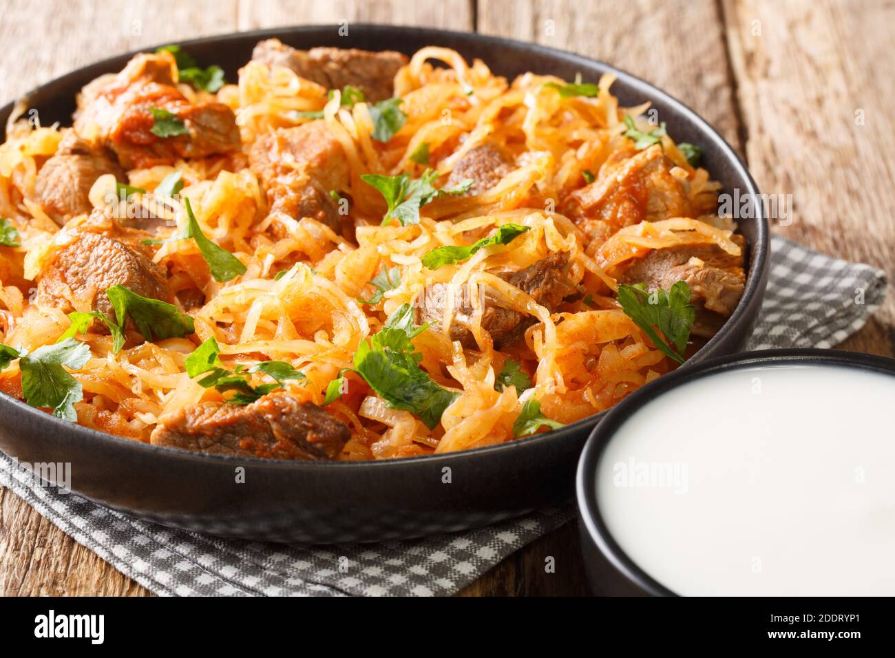 Sauerkraut stew with pork and paprika close-up in a plate on the table. horizontal Stock Photo