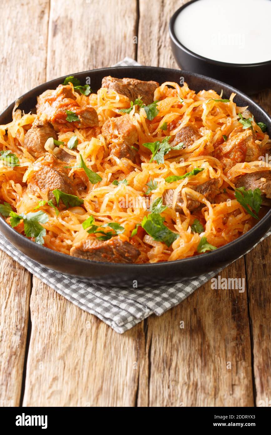 Szekely Gulyas or Szegedin goulash with pork, onions and sauerkraut in a paprika broth closeup  in the plate on the table. Vertical Stock Photo