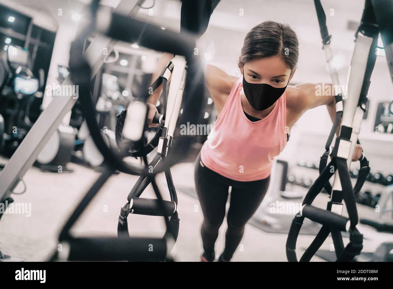 Woman training at gym wearing face mask for Coronavirus prevention while exercising strength indoors Stock Photo